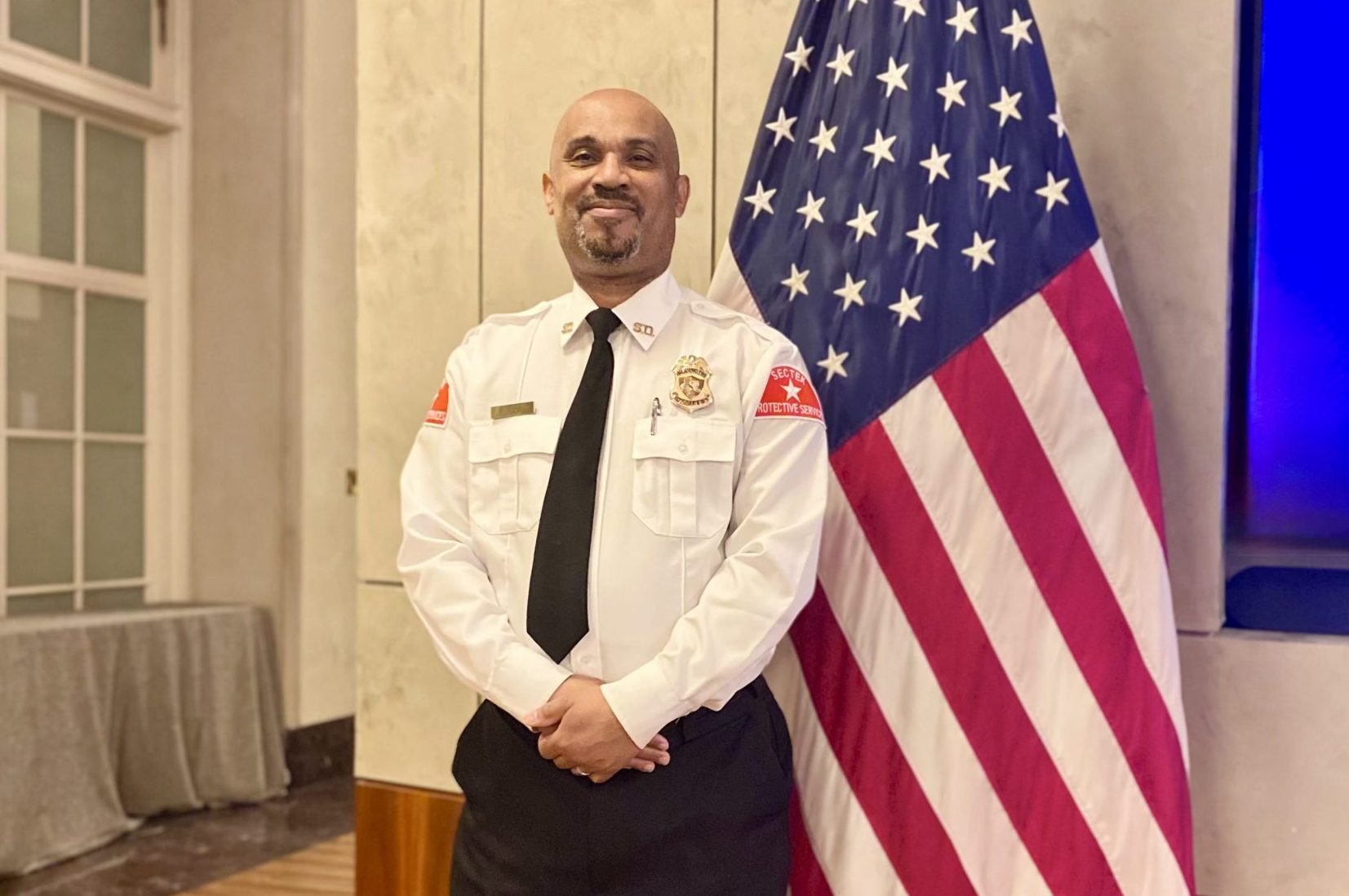 SecTek officer standing post near an American flag